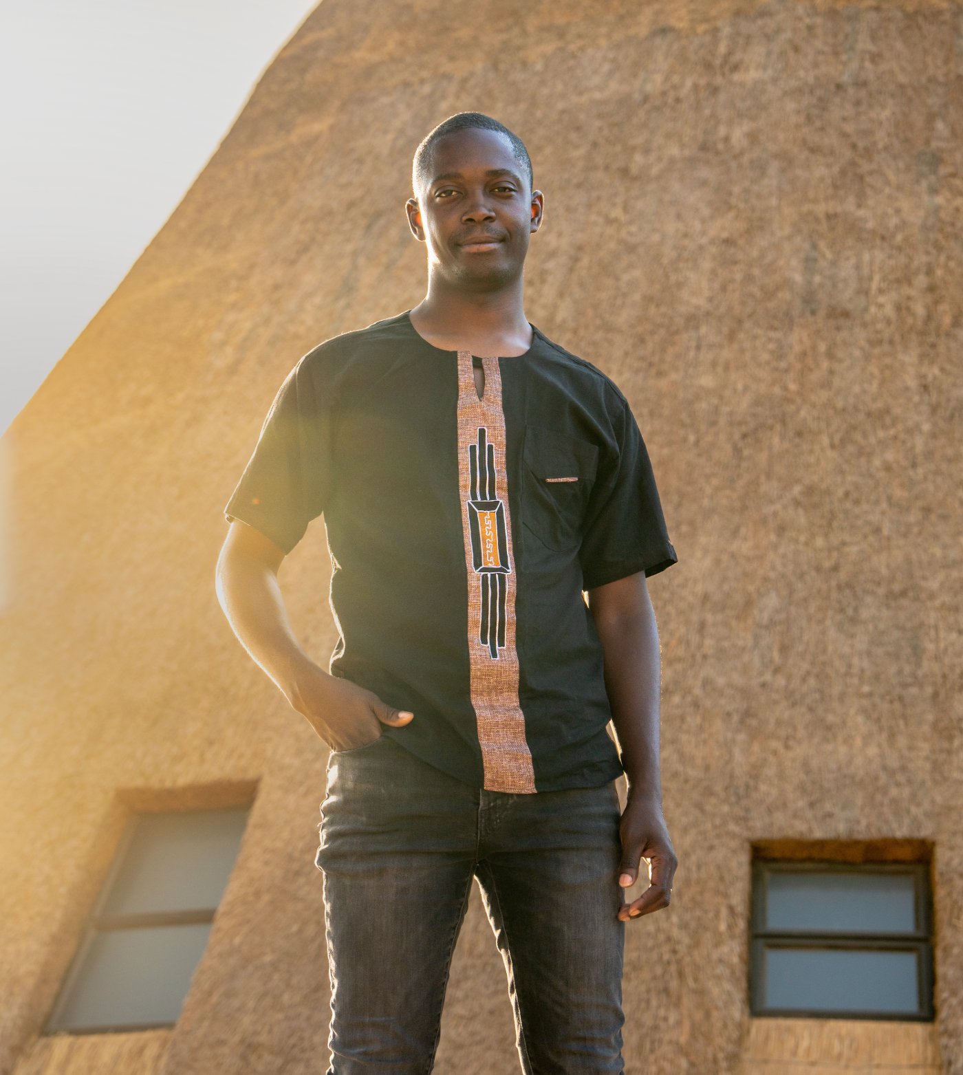 Emmanuel Nawa Kamuna standing in front of a thatched hall at the Umodzi Epicentre