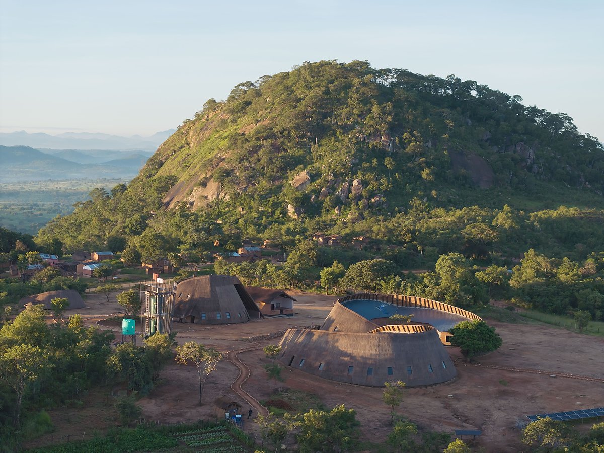 Umodzi Epicentre: thatched buildings at the foot of a wooded hill